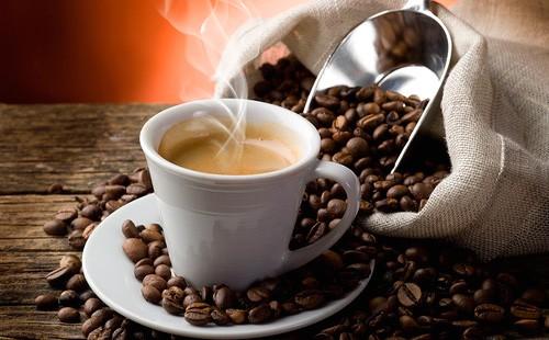 Чашка с кофе на фоне рассыпанного мешка кофейных зерен