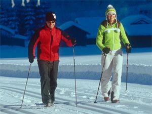 Семейная пара зимой занимается скандинавской ходьбой