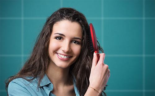 Молодая женщина расчесывает волосы